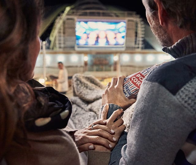 couple watching movie under the stars while sharing popcorn